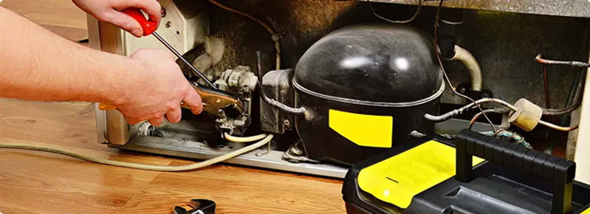 Refrigerator repair technician fixing the compressor and wiring in Medina, WA