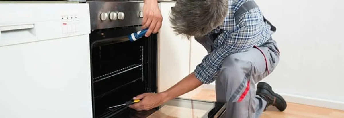 Oven repair technician inspecting and servicing an electric oven in Bellevue, WA