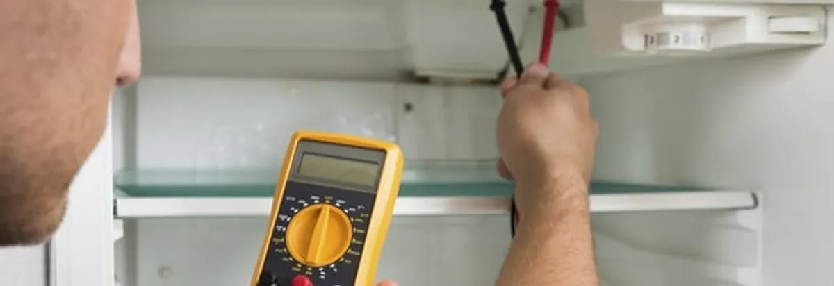 Refrigerator repair technician testing electrical components with a multimeter in Bellevue, WA
